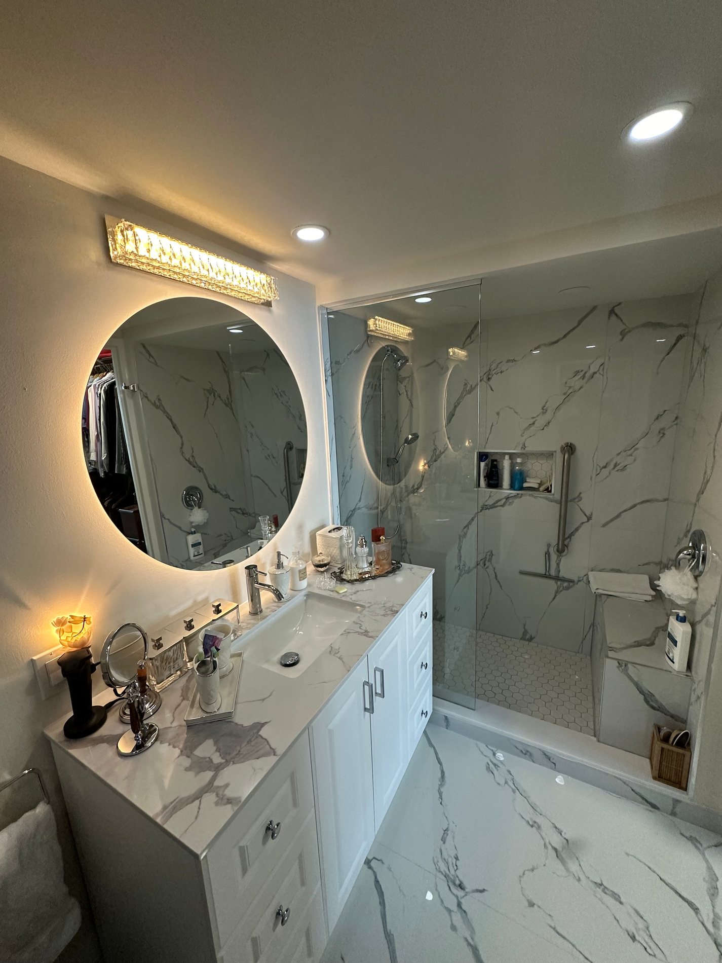 Marble ensuite with a backlit round mirror, by Ace Contracting