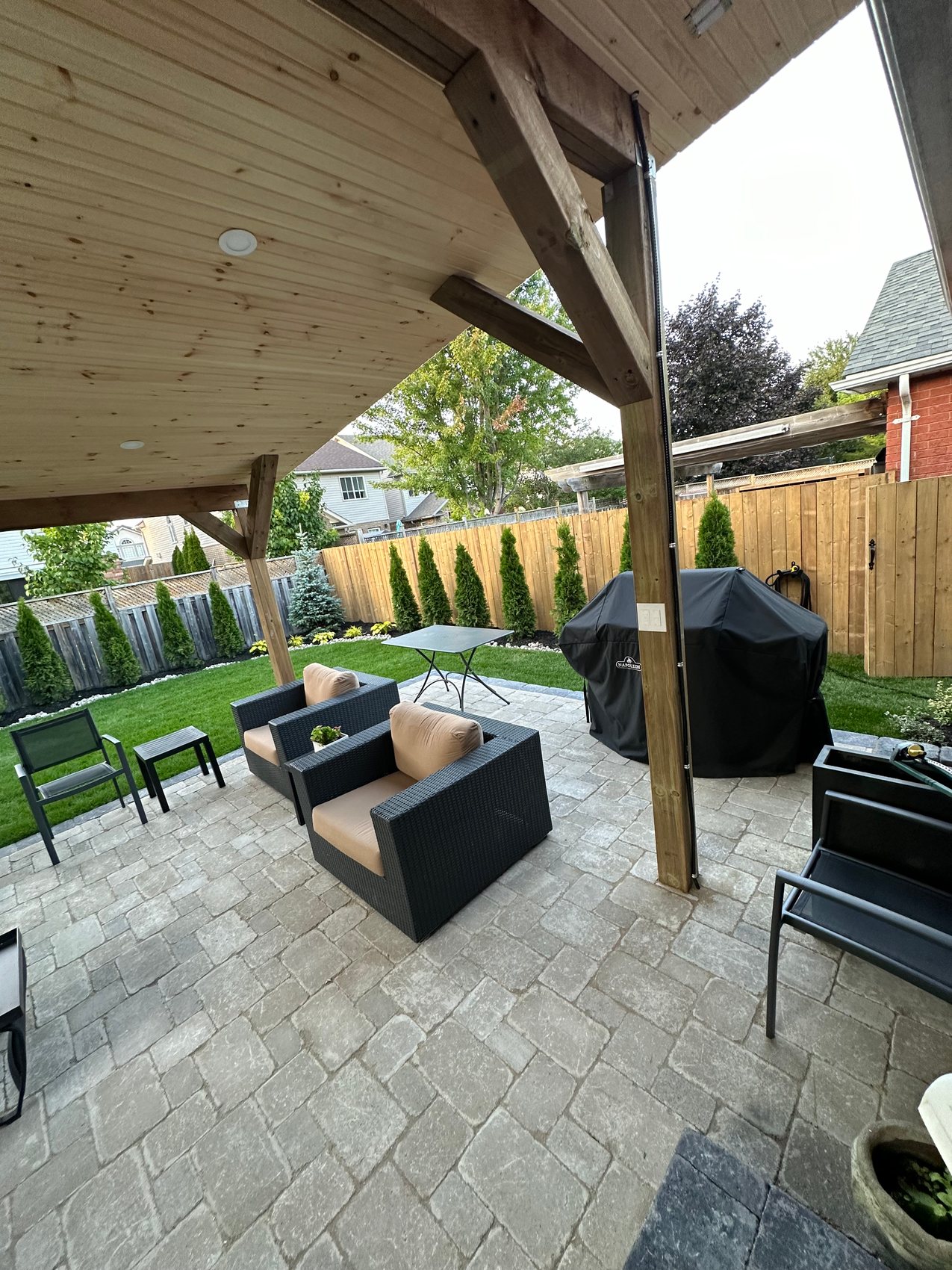 Covered outdoor lounge with timber structure and stone patio